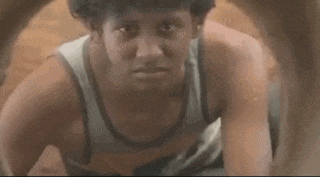a man in a tank top is crying while crawling through a hole in the ground .
