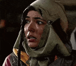 a woman wearing a scarf around her head is making a sad face .