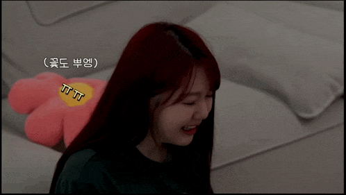 a woman with red hair is sitting on a couch next to a stuffed flower that says tttt