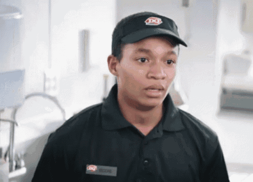 a young man wearing a dq hat and a black shirt looks at the camera