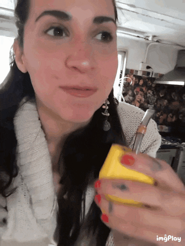 a woman in a white sweater is holding a yellow object in her hand with imgplay written below it