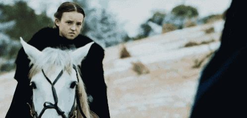 a little girl is riding a white horse in the snow .