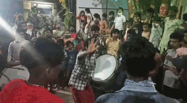 a man is playing a drum in front of a crowd