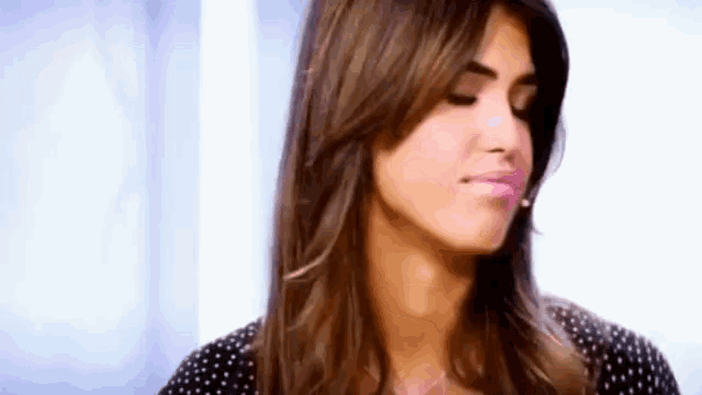 a woman with long hair is making a funny face while wearing a polka dot shirt .