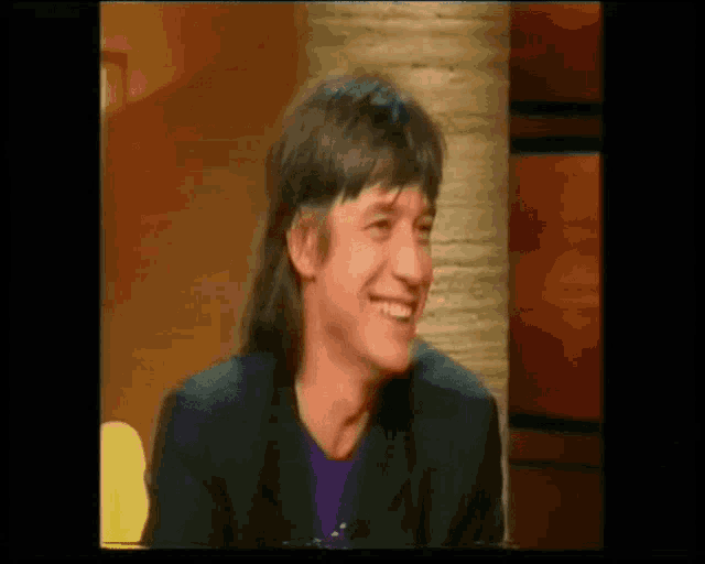 a man with long hair is smiling in a video