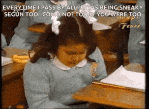 a girl is sitting at a desk in a classroom with a banana in her hand .