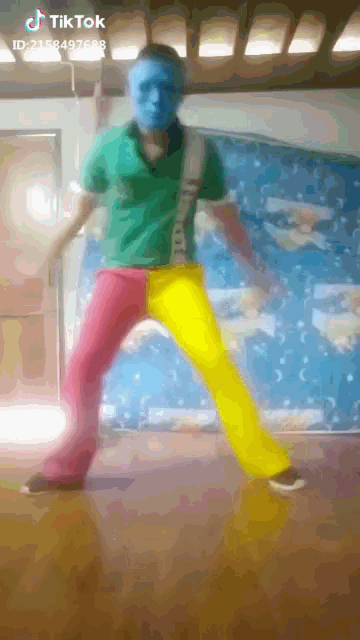 a man wearing a blue mask and colorful pants is dancing in front of a wall that says tik tok on it