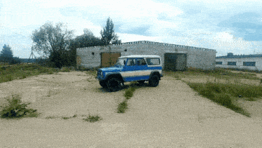 a blue and white jeep is parked in front of a white building