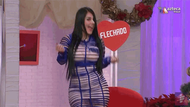 a woman in a blue and white dress is holding a heart that says flechado