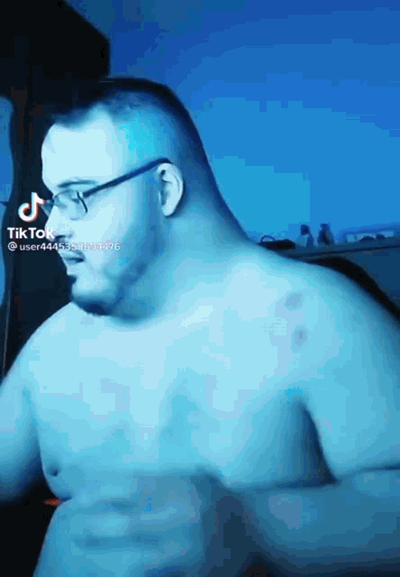 a shirtless man with glasses and a tattoo on his chest is dancing