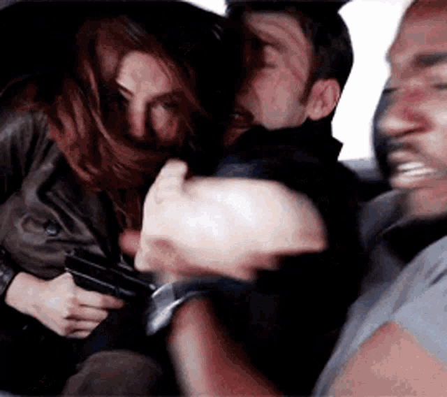 a woman is holding a gun next to a man and a woman .