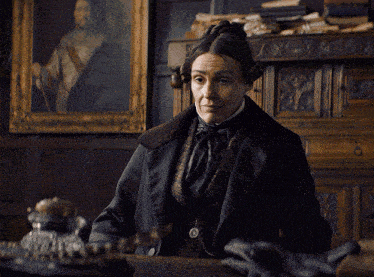 a woman sitting at a desk with a clock on it
