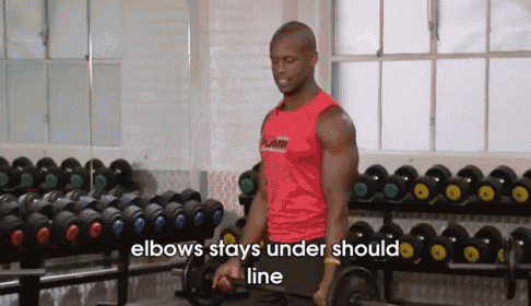 a man is lifting a barbell in a gym with the words `` elbows stays under should line '' .