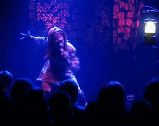 a woman singing into a microphone in front of a crowd