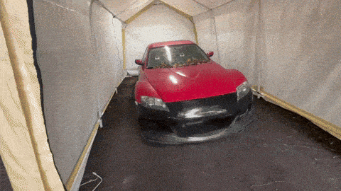 a red car is parked inside a tent