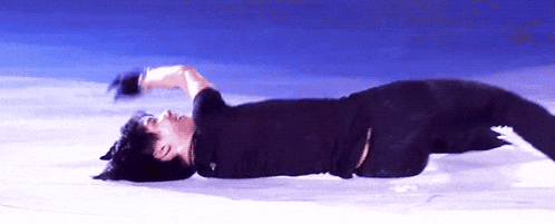 a man in a black shirt is laying on his back on the ice