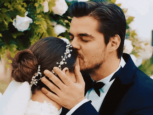 a bride and groom kissing with the bride wearing a tiara