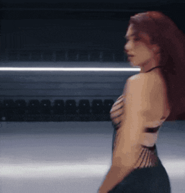 a woman with red hair is standing in front of empty seats in a stadium .