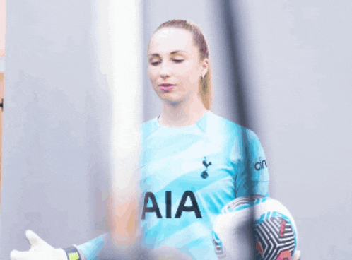 a woman in a blue aia jersey holds a ball