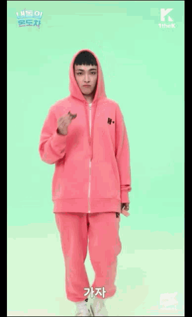 a man in a pink hoodie and pink sweatpants is holding a piece of food .
