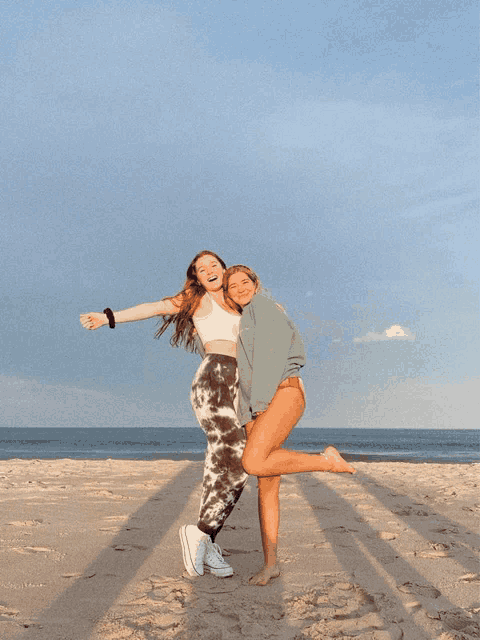 two girls posing for a picture on a beach with one wearing a sweatshirt that says calvin klein