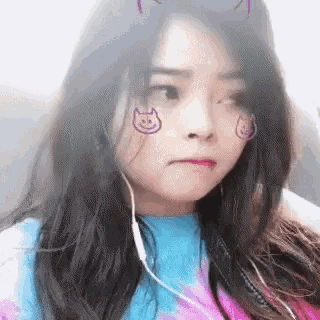 a woman wearing headphones and a tie dye shirt with a cat on her face .