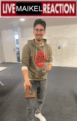 a man holding a piece of chocolate in front of a sign that reads live maikel reaction