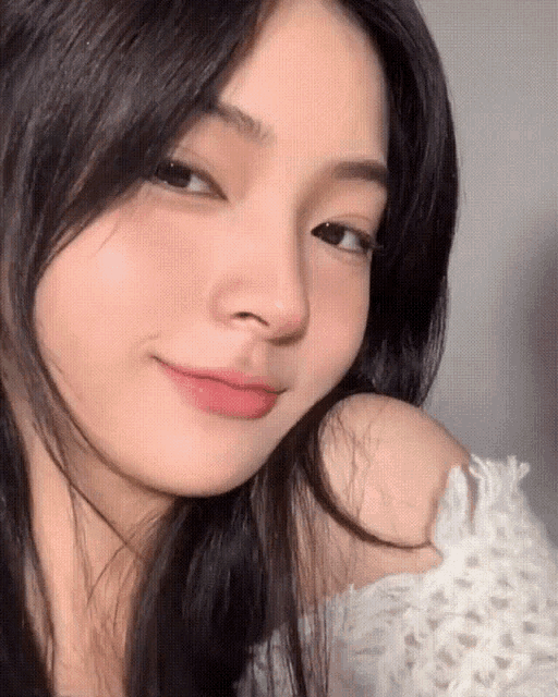 a close up of a girl 's face with a white sweater on