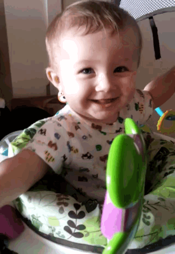 a baby is sitting in a walker and smiling