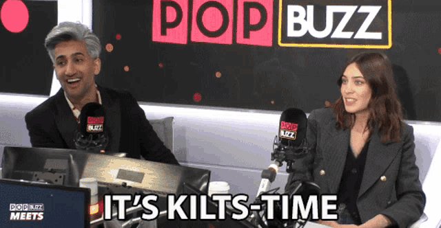 a man and a woman are sitting in front of a pop buzz logo