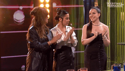 three women are clapping in front of martinez hermanos