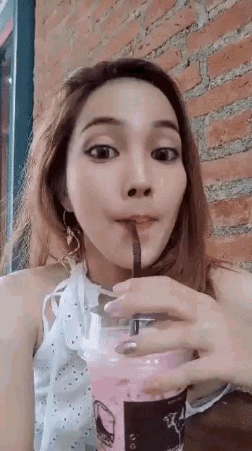 a woman drinking from a cup with a straw in her mouth