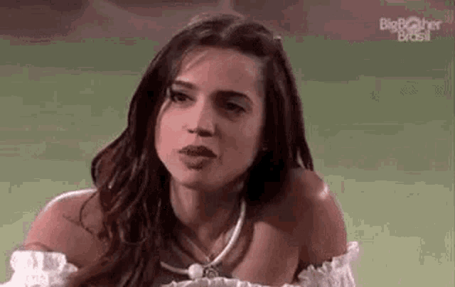a woman is making a funny face while sitting on a green field .