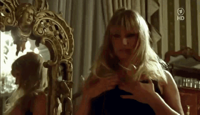 a woman is looking at herself in a mirror with the number 1 on the bottom left
