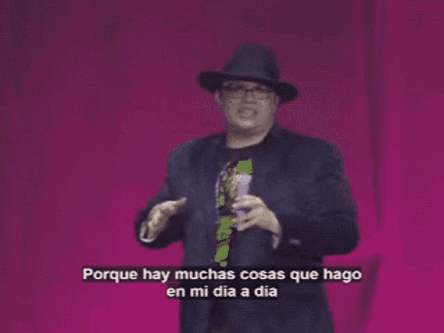 a man in a suit and hat is speaking in spanish