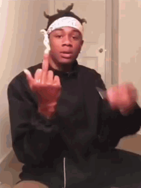 a young man wearing a bandana and a black jacket is giving the middle finger .