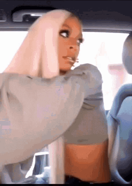 a woman with long blonde hair is sitting in the back seat of a car