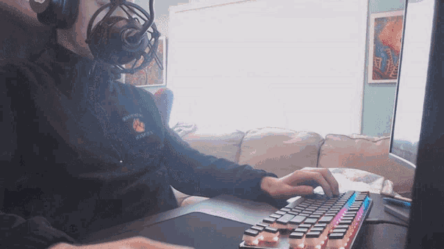 a man wearing headphones and a sweatshirt that says warriors on it is typing on a keyboard