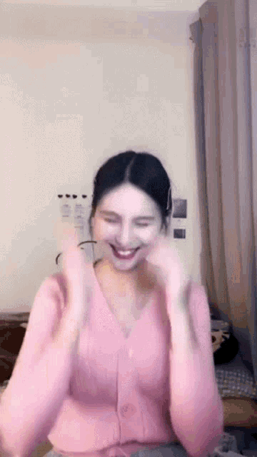 a woman in a pink cardigan is making a face