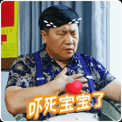 a man in a blue shirt and suspenders is holding a red object in his hand and has chinese writing on his chest