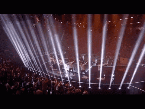 a group of people are dancing in a circle of lights