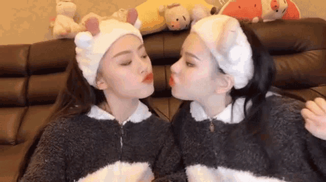 two women wearing headbands are kissing each other on the cheek .