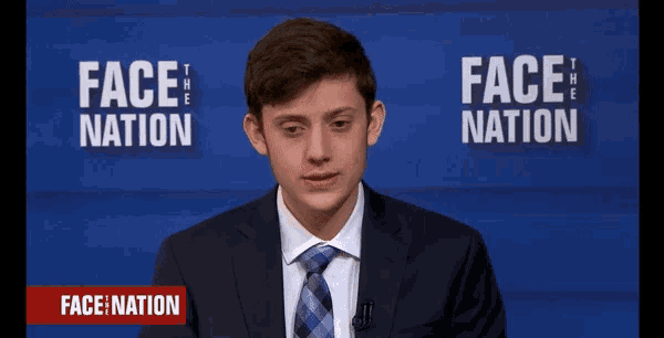 a man in a suit and tie stands in front of a sign that says " face nation "