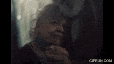 an older man with a beard and long hair is looking at the camera .