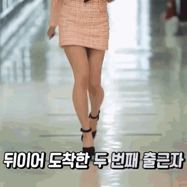 a woman is walking down a hallway wearing a short skirt and heels .