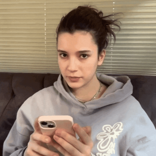 a woman wearing a hoodie that says s on it is holding a cell phone