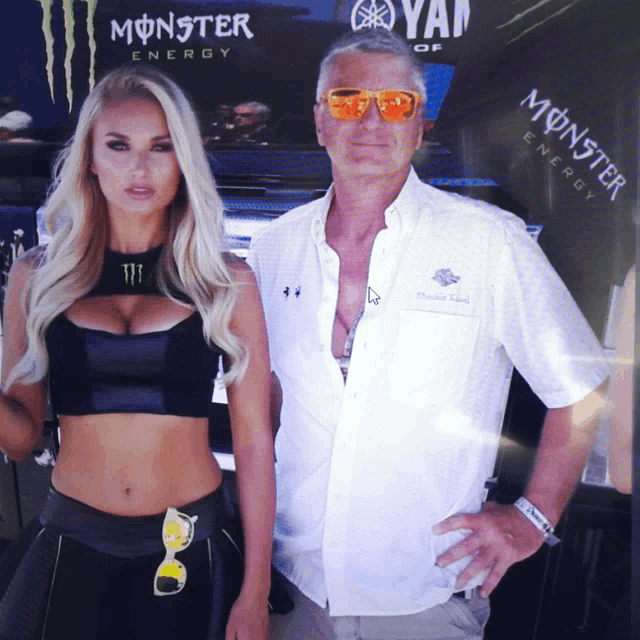 a man and a woman are posing for a picture in front of a monster energy sign