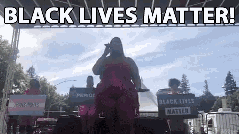 a woman in a pink dress is standing on a stage holding a microphone .