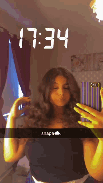 a woman is taking a selfie in front of a mirror with the time 17:34