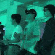 a group of people standing in a room with a green light behind them